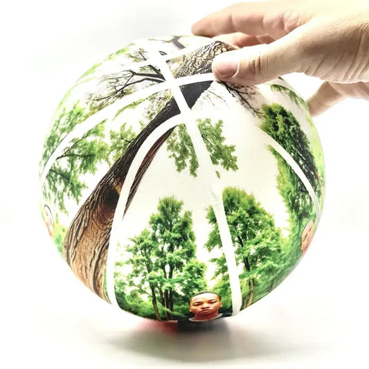 Basketball fabric cover on a globe with nature-themed design held by a hand on a white background
